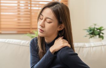 A woman massaging her sore shoulder.