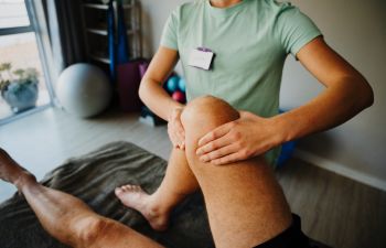 A physical therapist examining a man with knee injury.