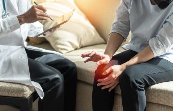 A doctor consulting a woman with knee pain.